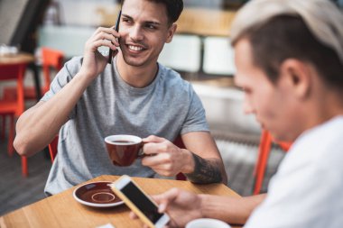 İyimser erkekler telefonlar ile masada çalışıyor
