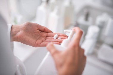 Beyaz plastik pompa konteyner basarak kadın kol ve başka bir kol üzerinde köpük alarak kapatmak