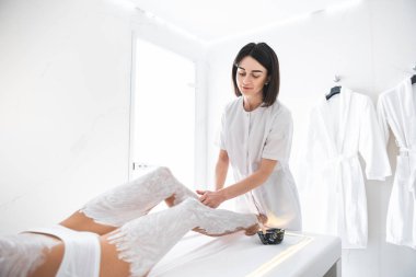 Sevinç ile çalışma. Cilt Bakımı yordamı spa kabine sahip beyaz iç çamaşırı kız. Şevval özçelik güzellik hafifçe dokunarak Bayan alt bacak beyaz laboratuarında