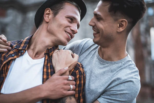 Счастливый мужчина обнимает уходящего друга во время разговора — стоковое фото