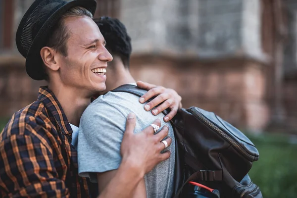 Blij mannelijke knuffelen kameraad tijdens wandeling buiten — Stockfoto