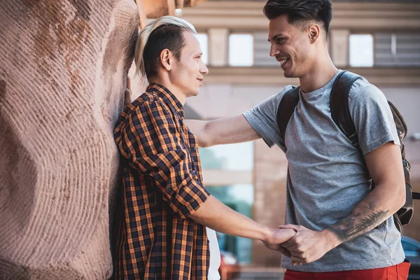 Fröhliche Männer, die erzählen und die Arme zusammenhalten — Stockfoto