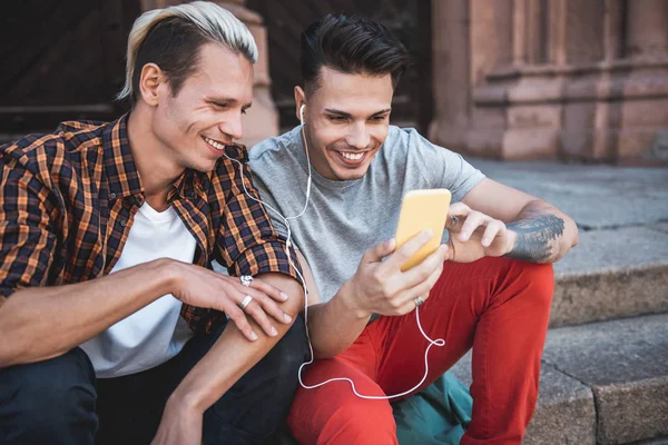 Glada män höra musik med headset utomhus — Stockfoto