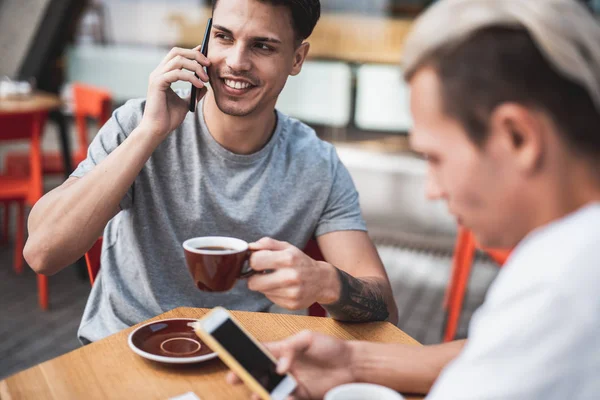 Optimistiska män som arbetar med telefoner vid bord — Stockfoto