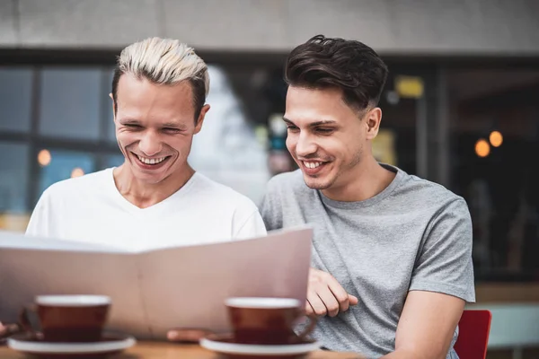 Lyckliga män att välja rätter på kort utomhus — Stockfoto