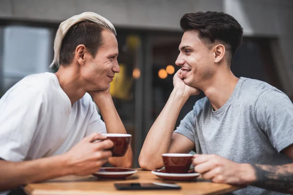 Tevreden vrienden proeverij kopjes koffie buiten — Stockfoto