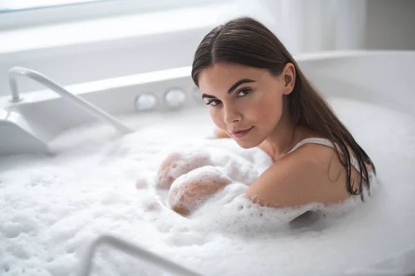 Calm woman resting in water with foam — Stock Photo, Image