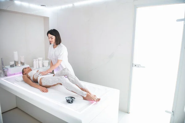 Beautiful girl in white lingerie having massage with white clay — Stock Photo, Image