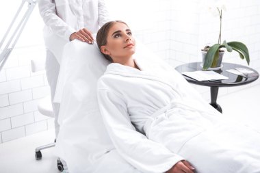 Spa zevk. Sağlık yordamı için bekleyen olumlu genç kadın. Şezlong duran kırpılmış Kozmetik uzmanı