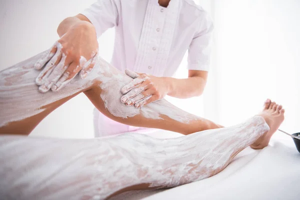 Esteticista fazendo massagem com barro branco para jovem — Fotografia de Stock