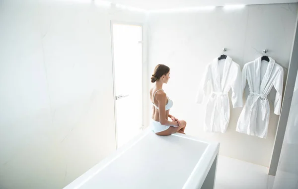 Uroczy młoda kobieta w białej bielizny i miękkie szlafroki na ścianie — Zdjęcie stockowe