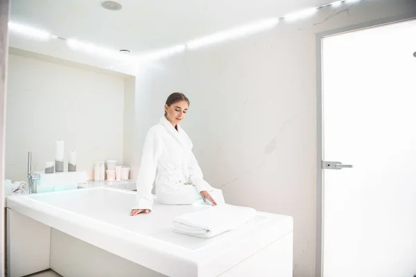 Lovely young lady sitting on massage desk at spa salon — Stock Photo, Image