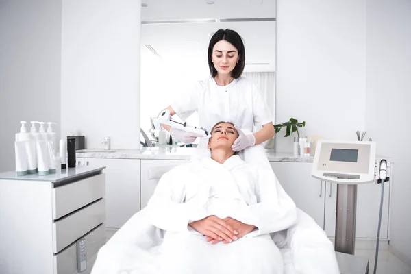 Atraktivní mladá žena ležící na válendu na kosmetička kabinetu přitom injekce ve tváři — Stock fotografie