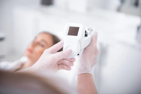 Kosmetolog händer i sterila handskar att trycka på knappen på elektroniska nålförare — Stockfoto