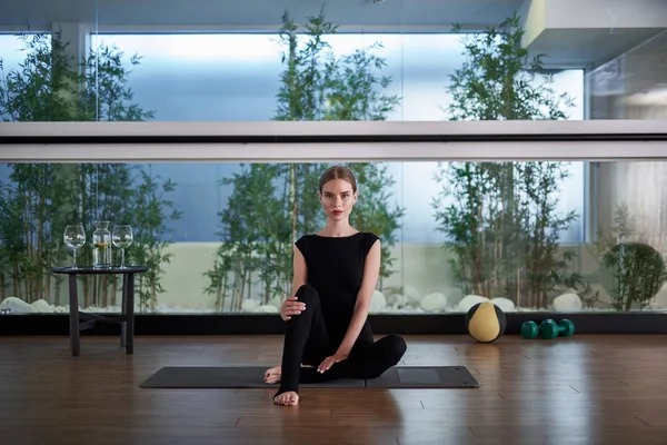 Yoga mat üzerinde oturan sakin genç bayan
