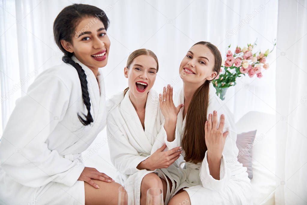 Cheerful girls celebrating friend engagement at spa salon