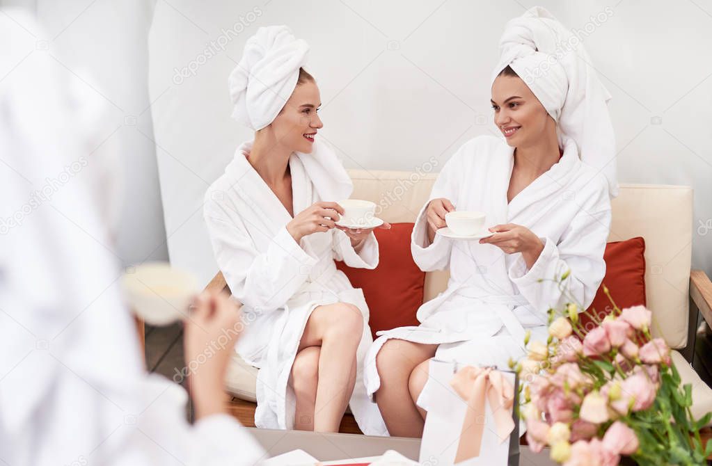 Cheerful girls enjoying tea at spa lounge