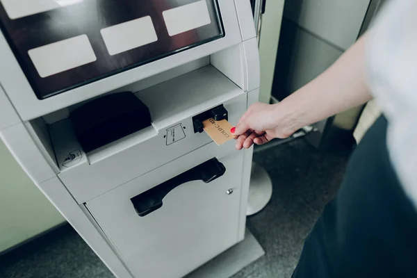 Woman is taking off bank card from cash dispenser