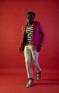 Neşeli adam kırmızı arka plan üzerinde yürüyor