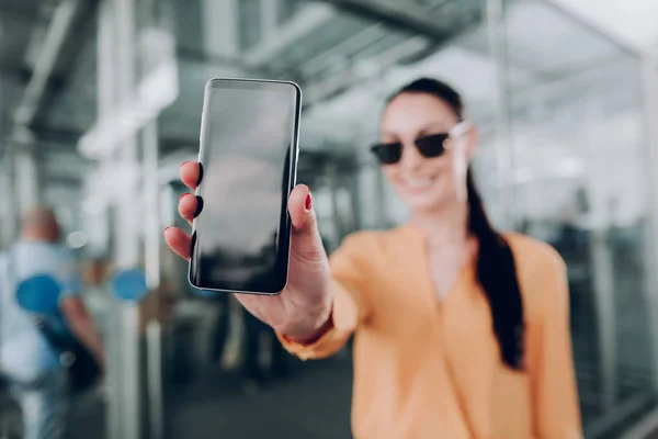 Jovem mulher está mostrando seu smartphone ao ar livre — Fotografia de Stock