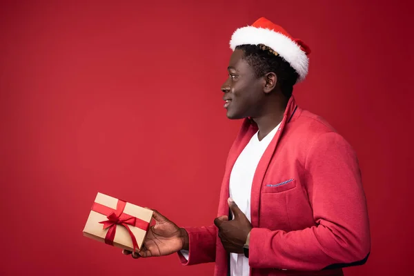 Vrolijke kerel houdt geschenk op rode achtergrond — Stockfoto