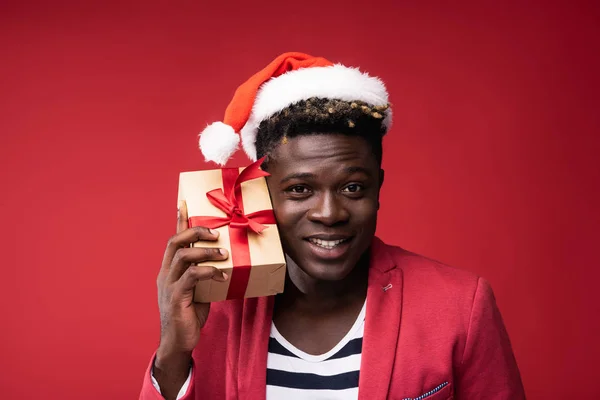 Glimlachende man houdt geschenk in de buurt van oor — Stockfoto