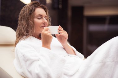 Sıcak bir içecek fincan holding beyaz bornoz çekici Bayan