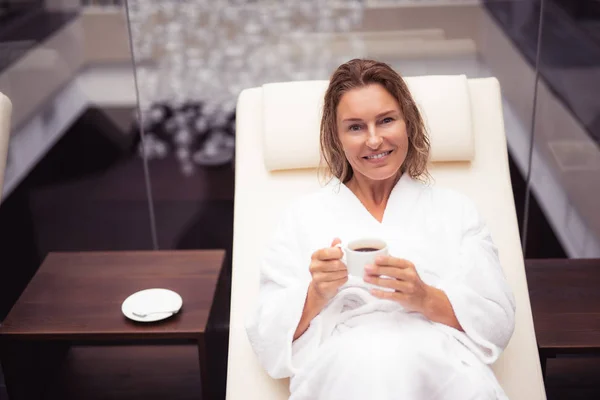 Attraktive Dame mittleren Alters im weißen Bademantel mit einer Tasse Kaffee — Stockfoto