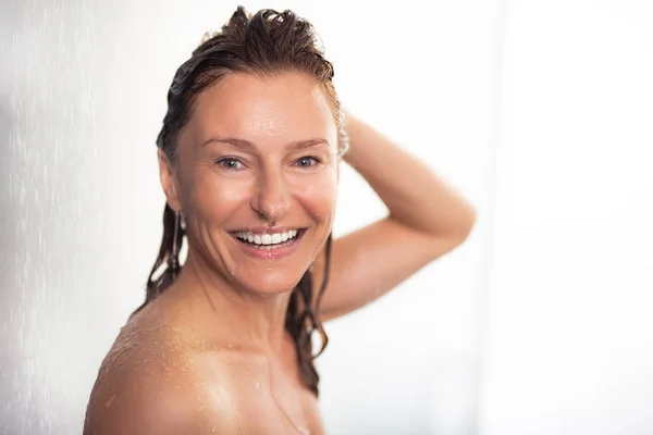 Atractiva mujer desnuda tomando ducha y tocando el cabello —  Fotos de Stock