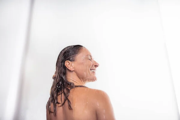 Приваблива гола жінка приймає душ на білому тлі — стокове фото