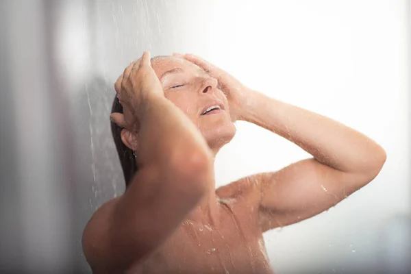 Hermosa mujer de mediana edad con las manos en la cabeza tomando ducha —  Fotos de Stock