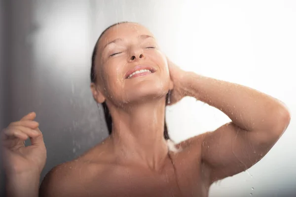Красива жінка середнього віку приймає душ і посміхається — стокове фото