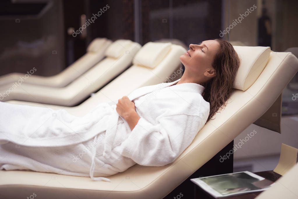 Charming middle aged woman with wet hair lying on daybed
