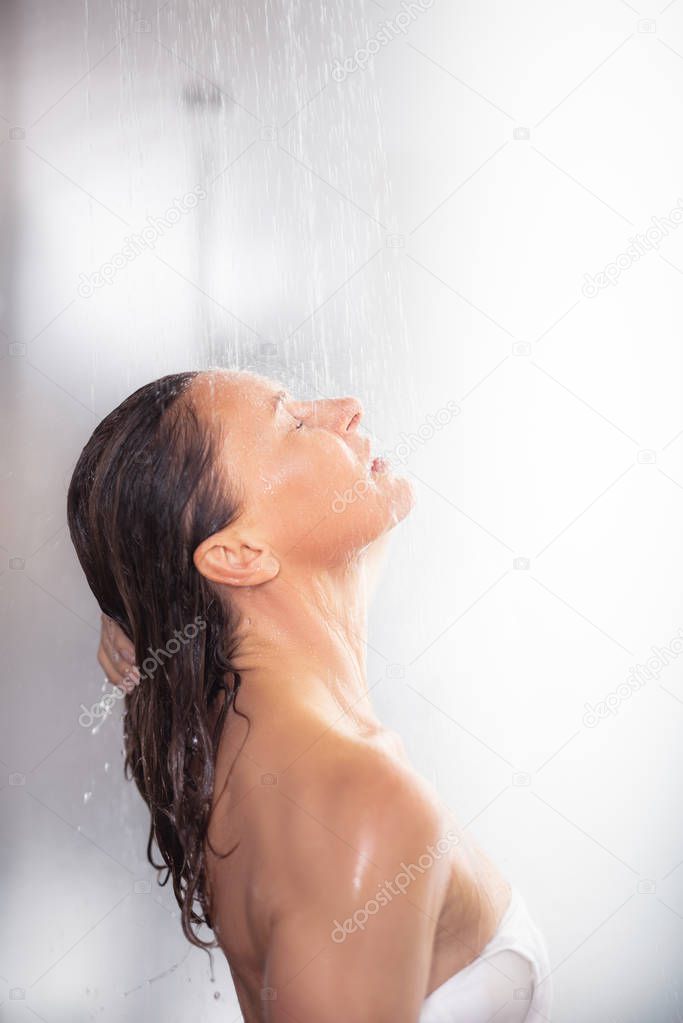 Beautiful middle aged lady with closed eyes taking shower
