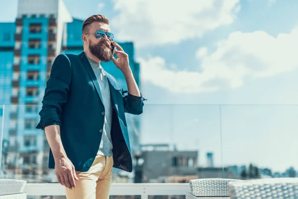 Alegre hombre sin afeitar hablando en móvil al aire libre — Foto de Stock