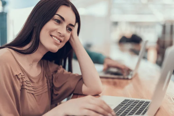 Lachende vrouw met behulp van zakboekje computer tijdens werk — Stockfoto