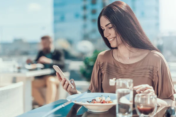 Optimistiska dam med mobila under lunchen utomhus — Stockfoto