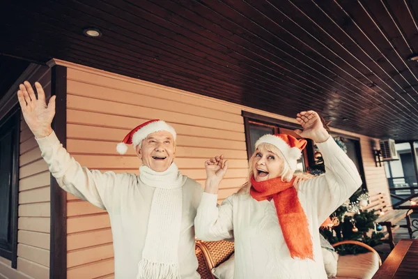 Veselý starší dvojice červených čepičkách na Vánoce — Stock fotografie