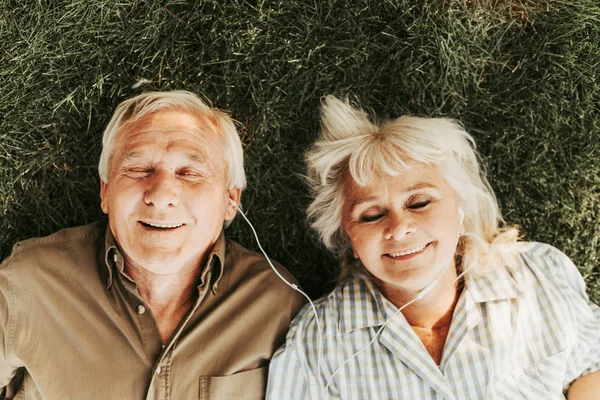 Alegre anciano dos relajante usando auriculares pequeños — Foto de Stock