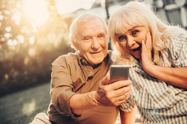 Casal de cabelos grisalhos olhando para a tela do smartphone — Fotografia de Stock