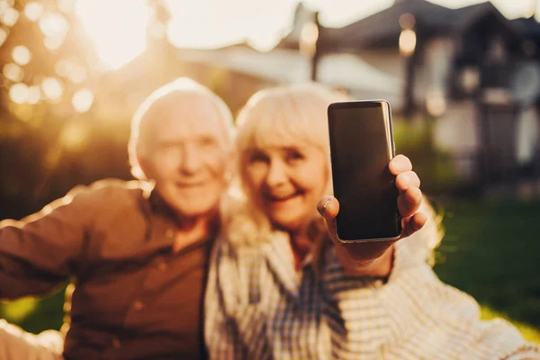 Smartphone in der Hand einer reifen Frau im Fokus — Stockfoto