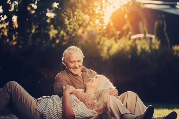 Relajada pareja de ancianos que se encuentra fuera en el césped — Foto de Stock