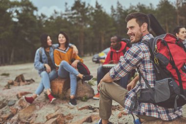 Arkadaşları ile açık oturan adam gülümseme