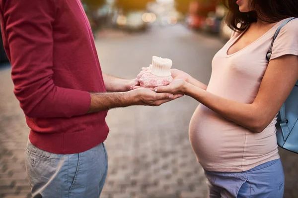 Junger Mann hält Frau die Hände mit süßen Babybooties — Stockfoto