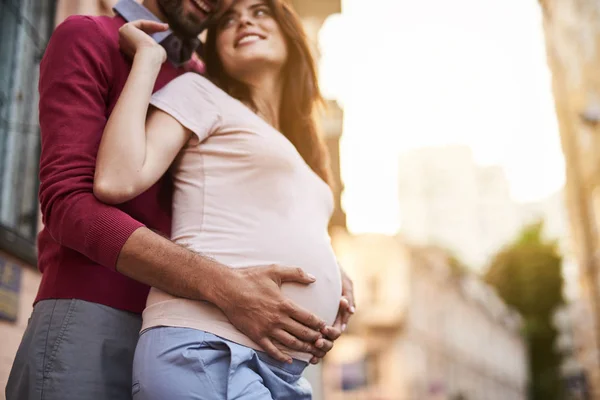 Усміхнений бородатий чоловік тримає животик своєї милої вагітної дружини — стокове фото