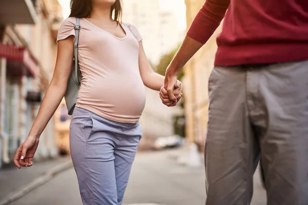 Junger Mann hält Hand seiner schönen schwangeren Frau — Stockfoto