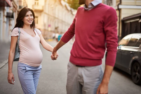 Junger Mann hält Hand seiner schönen schwangeren Frau — Stockfoto