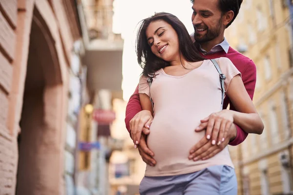 Glad skäggig man kramar hans gravida fru bakifrån — Stockfoto