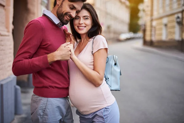 Gelukkige toekomstige ouders knuffelen in city straat — Stockfoto