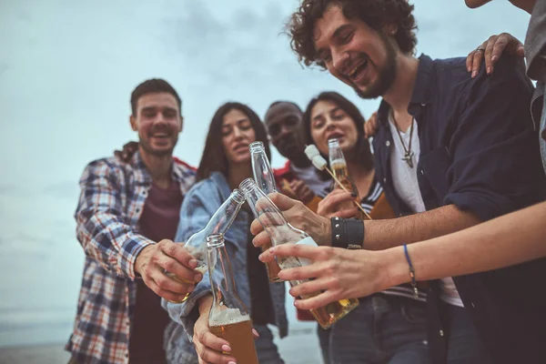 Amigos felizes batendo garrafas de vidro de cerveja — Fotografia de Stock